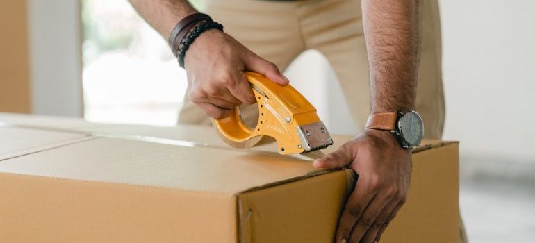 Person packing a box for long distance movers Detroit