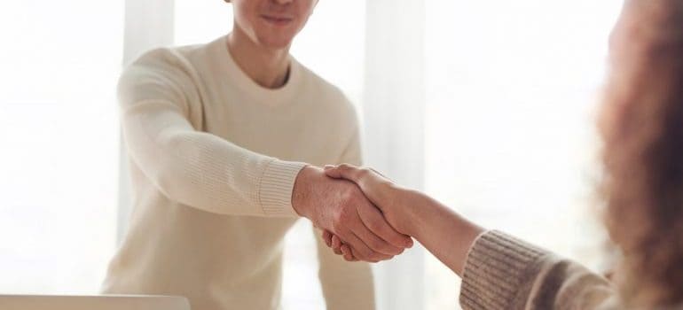 a team member of movers Belleville MI and a woman shaking hands