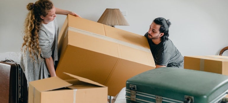 Man and woman carrying a box when moving