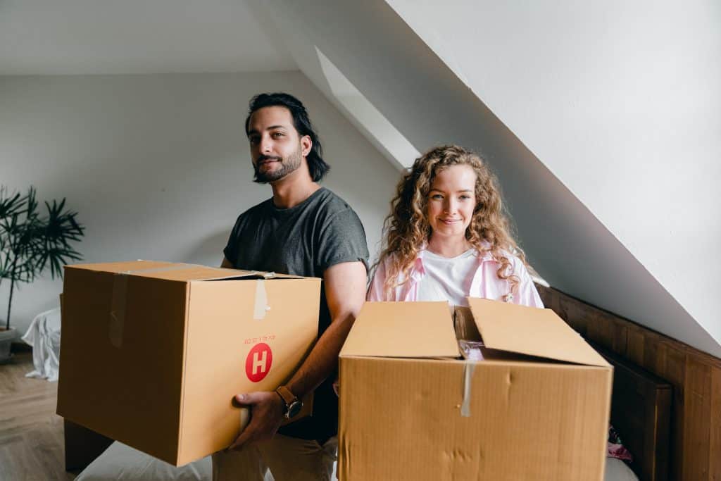 Young couple holding moving boxes