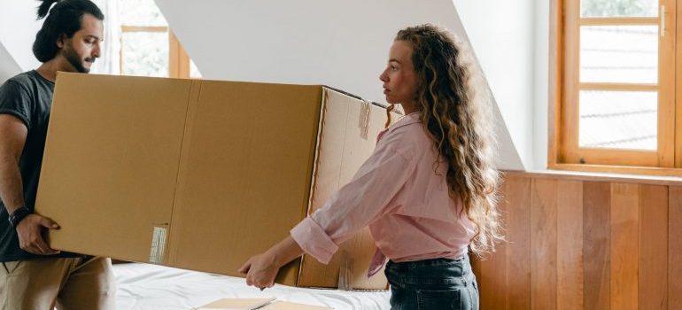 Two people carrying a big box.