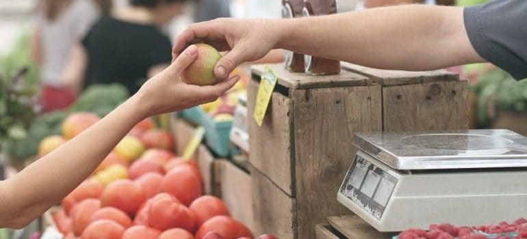 Two persons holding an apple in a farmers market