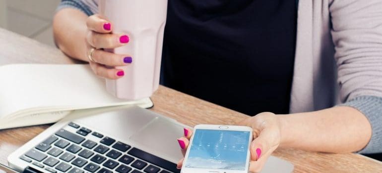 A woman in the office holding a phone and a cup of coffee