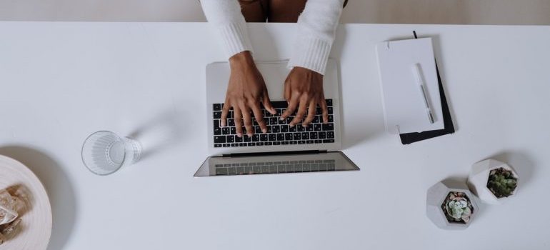 A person typing something on a white laptop.