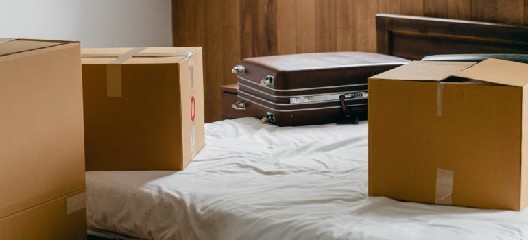 A bed with a cardboard box and a suitcase on it.