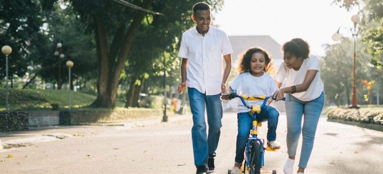 A family of three on the street with a child on a bike