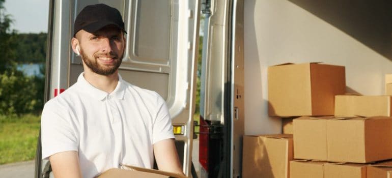 A smiling movers holding a box.