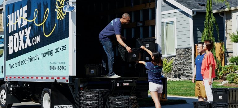 a couple standing by the side of a moving truck observing the loading process