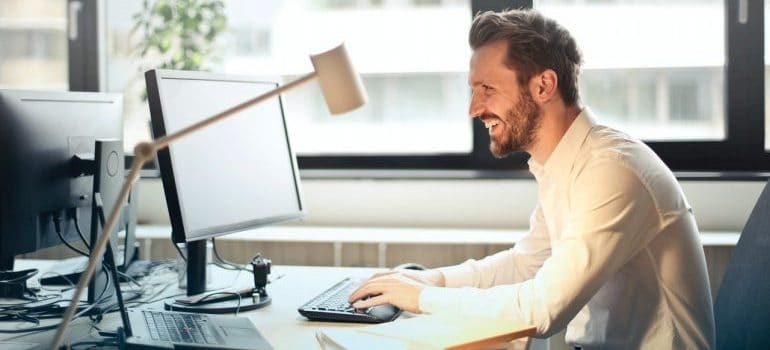 A man smiling while working on his office PC.