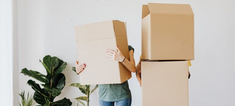 A couple holding a bunch of moving boxes.