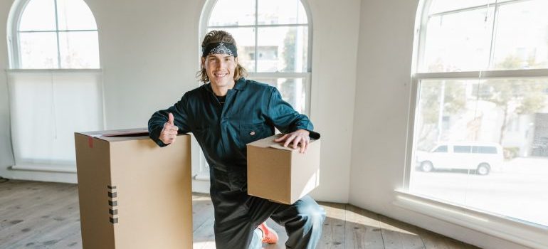 A mover kneeling and holding amoving box.